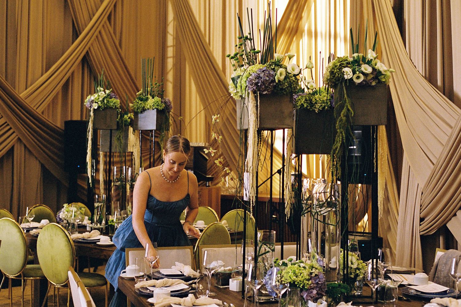 Mujer terminando de montar una mesa con flores altas