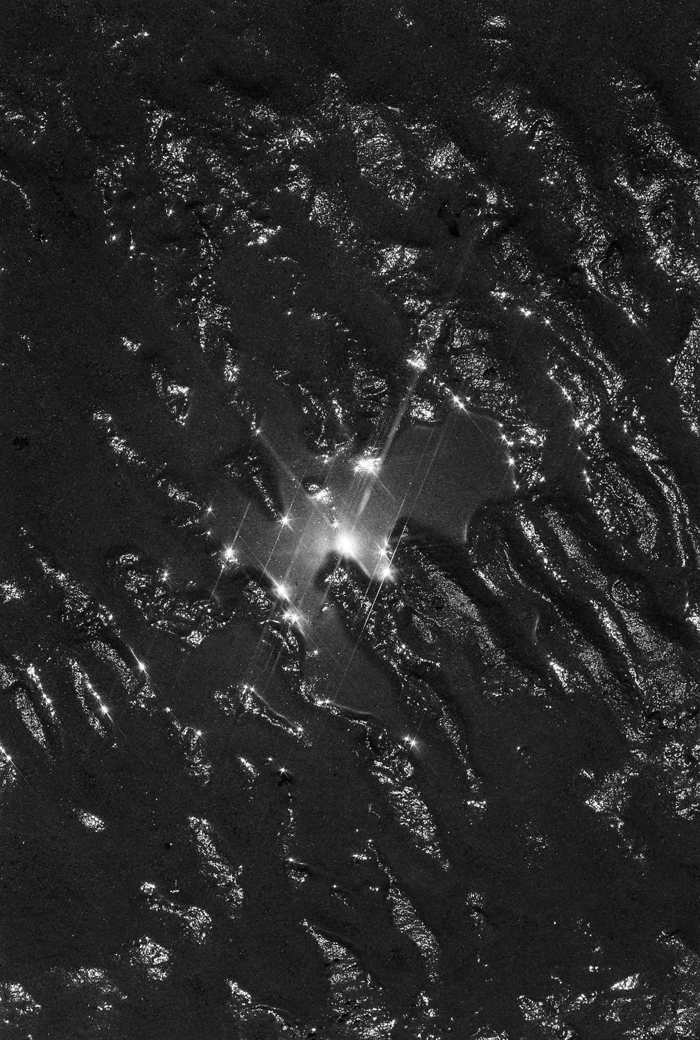 Brillos de luz sobre el barro de la marea