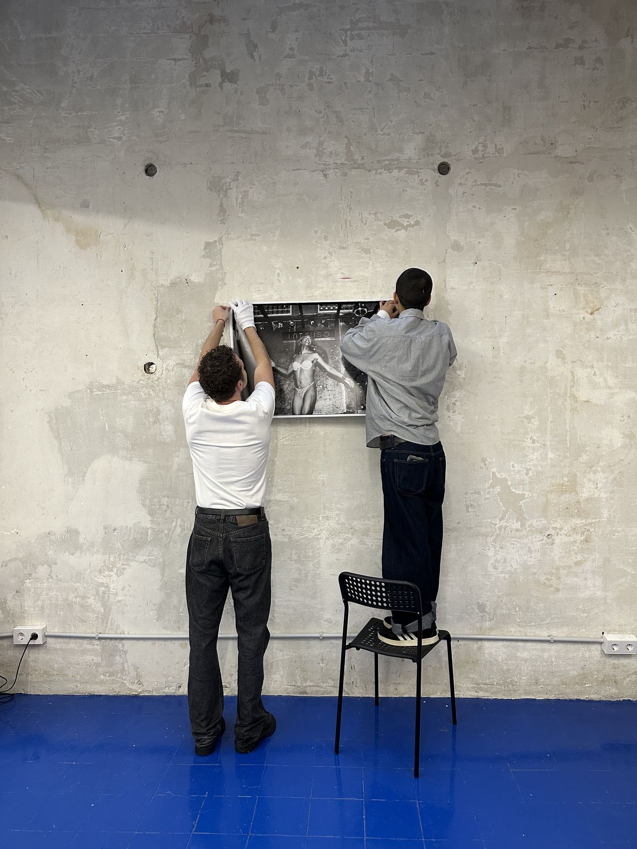 Dos personas colgando una fotografía en la pared