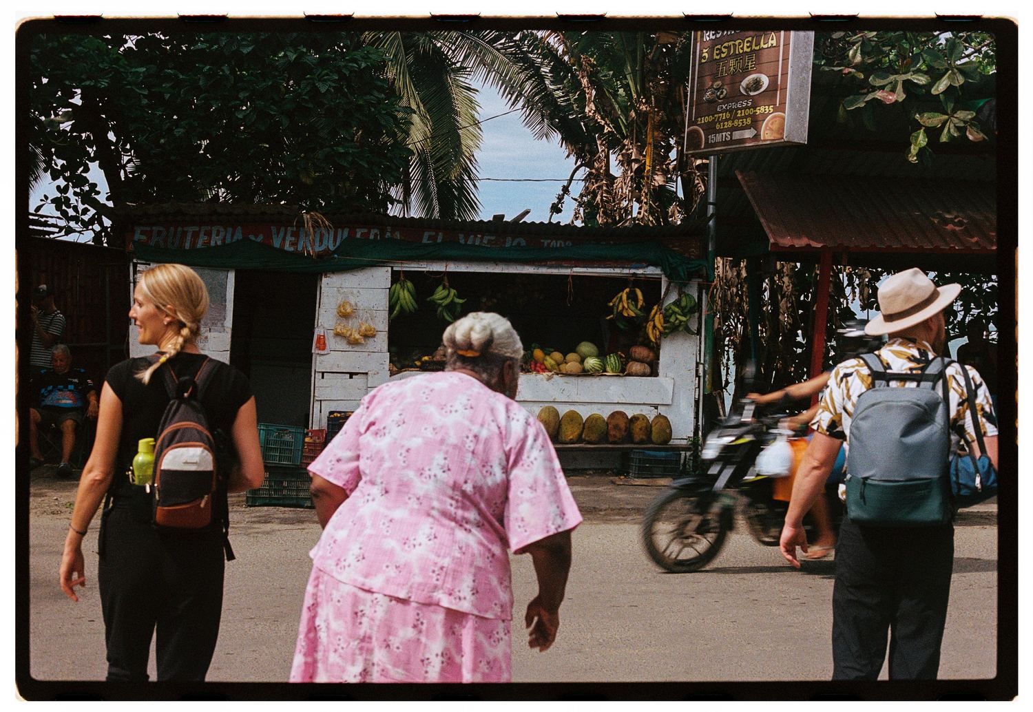 Calle con una frutería y gente pasando